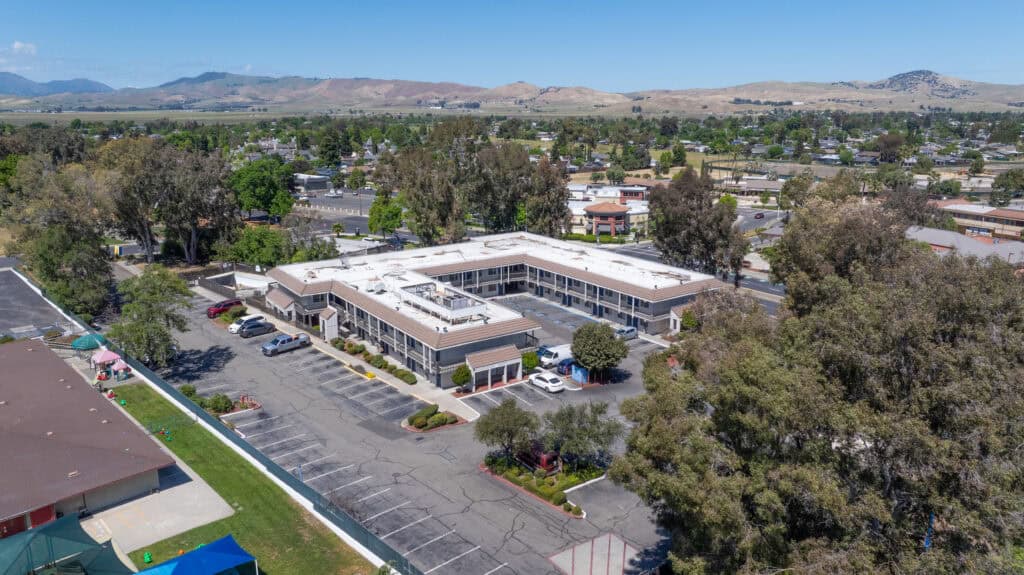 Aerial view of Super 8 Livermore hotel with parking lot and surrounding trees.