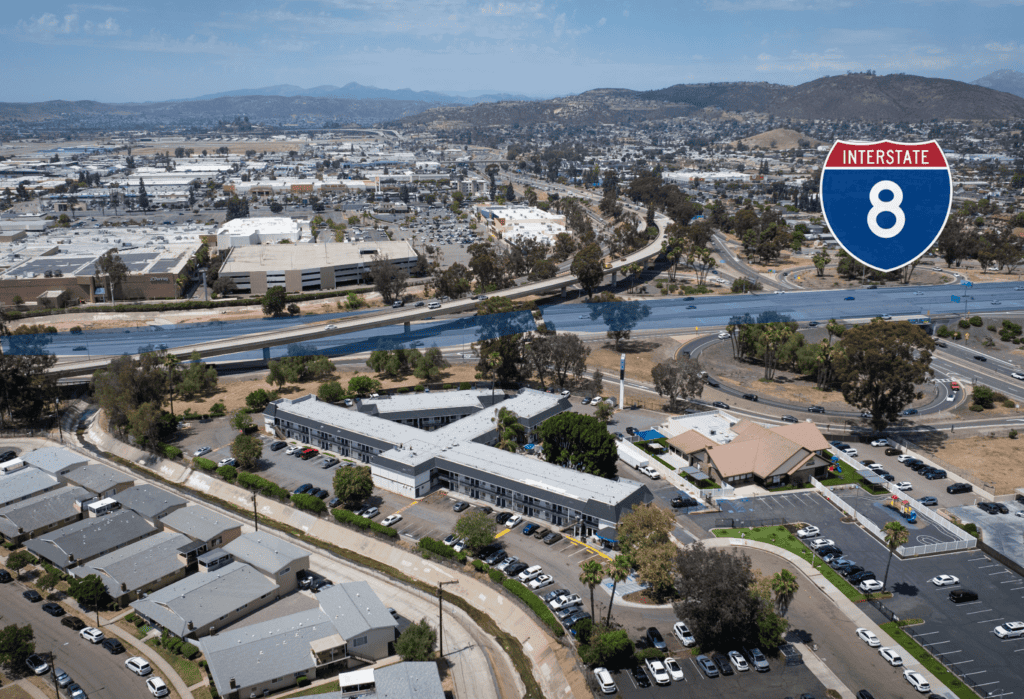 Aerial view of Interstate 8 in El Cajon with nearby buildings and mountains.